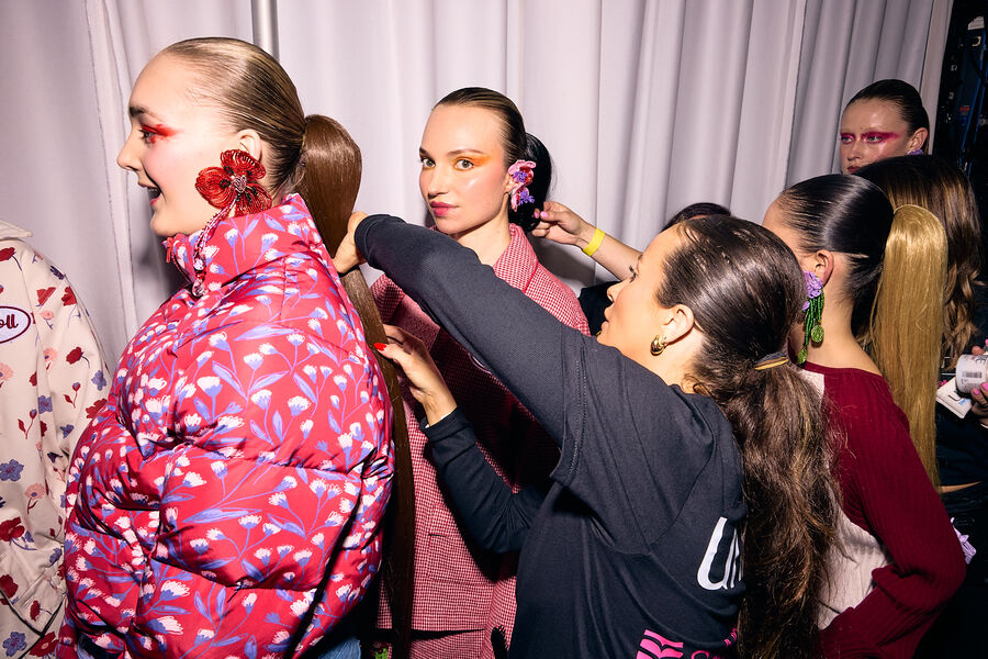Hair stylist preparing sleek ponytail runway looks backstage at London Fashion Week with Sally Beauty and UNITE Hair.